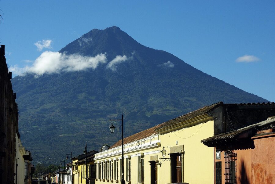 Cobblestone street in Antigua Guatemala with colonial buildings and Volcán de Agua in the distance