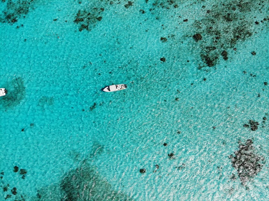 Aerial drone view of two boats anchored over clear turquoise water near the Belize Barrier Reef