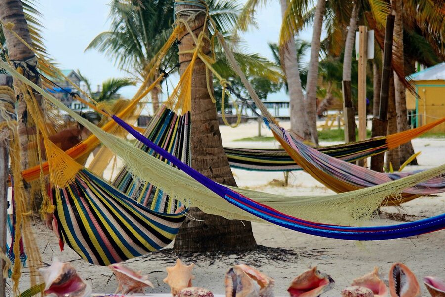Colourful striped hammocks strung between palm trees on the beach at Caye Caulker, Belize