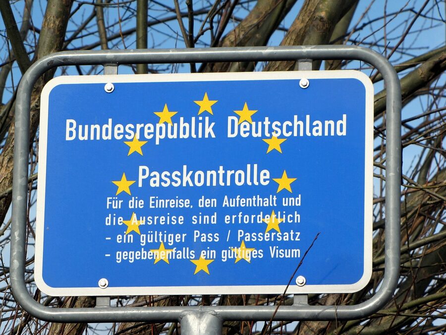 Blue border control sign in a wooded area indicating passport check is required