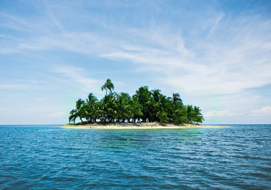 Tiny tropical island with palm trees in turquoise Caribbean water
