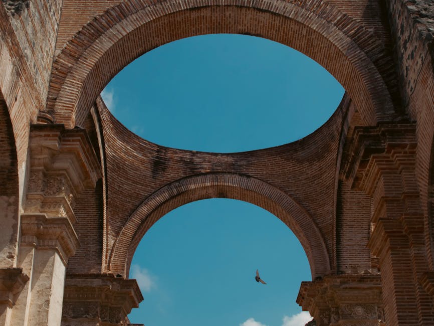 Historic stone arches at colonial ruin in Antigua Guatemala under blue sky