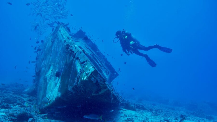 Scuba diver beside a Caribbean shipwreck on a reef bottom