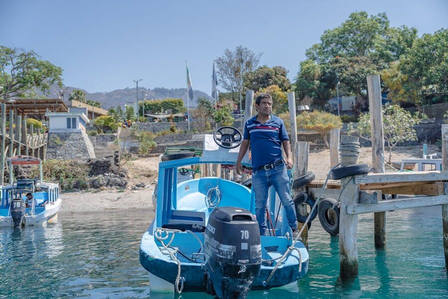 Man stands on a wooden boat docked at Panajachel pier on Lake Atitlan
