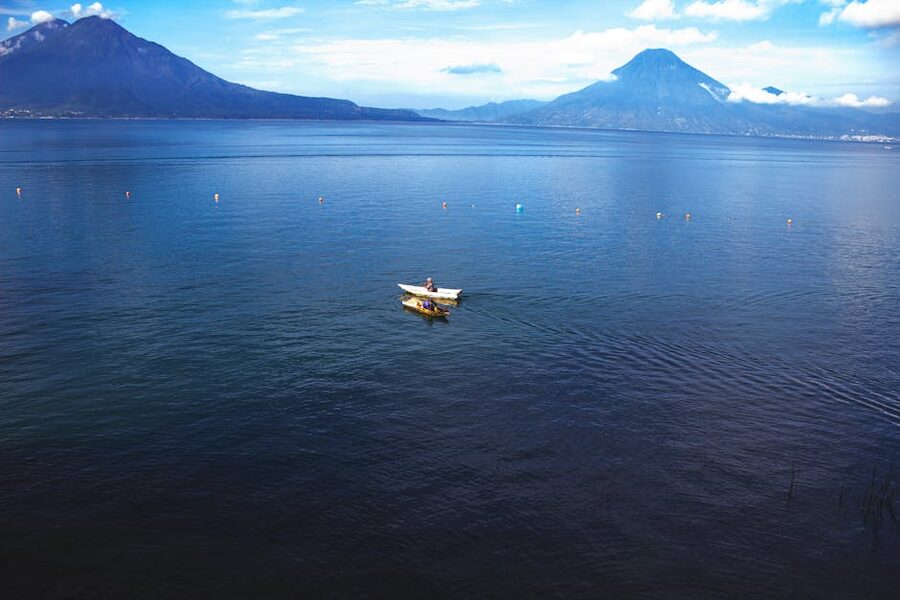 Calm Lake Atitlan with mountains in the background and a small boat in the distance