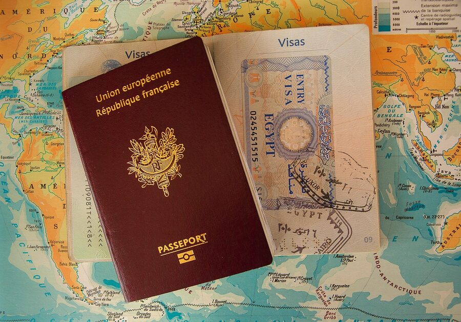European passport on top of a world map next to a paper visa with entry stamp