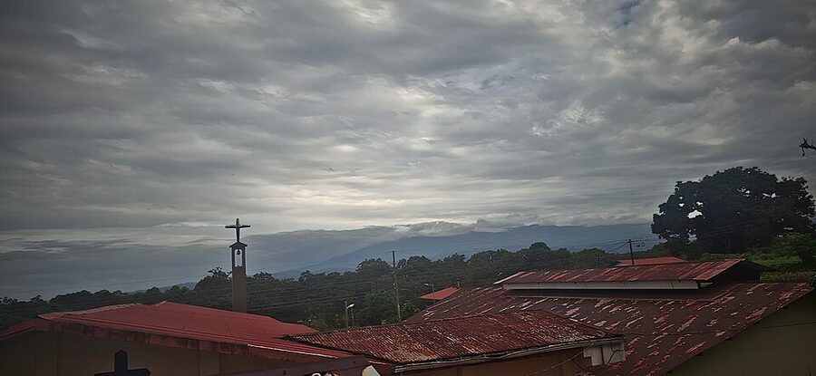 View of red-tiled rooftops near the Peñas Blancas border with mountains and clouds in the distance