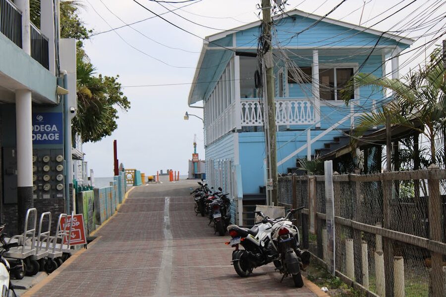 Pastel blue house on Utila Town's main street with motorbikes parked outside, Honduras
