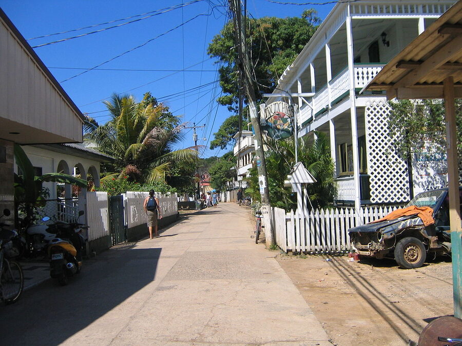 Wooden Caribbean houses on Utila Town's main road with a dive shop sign visible, Honduras