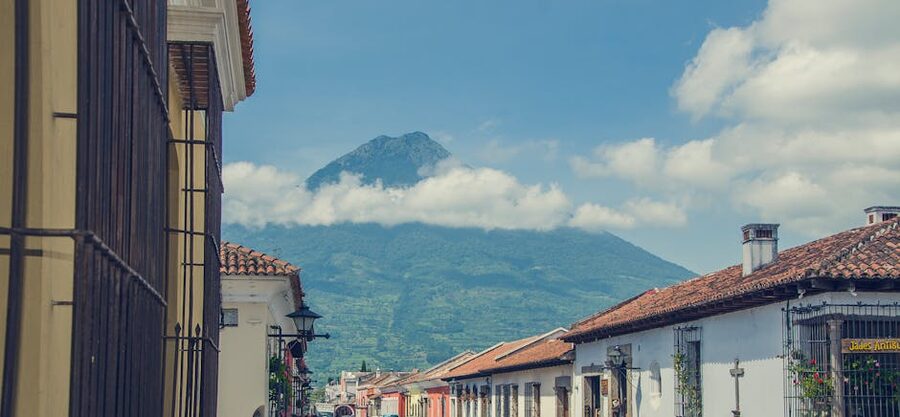 Cobbled street in Antigua Guatemala with volcano backdrop under cloudy sky