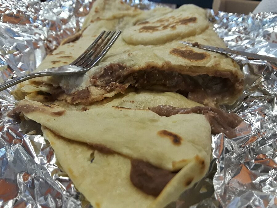 Cross-section of a Honduran baleada filled with refried beans cheese and crema